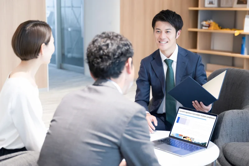 ノートパソコンと資料を用いて説明する不動産営業