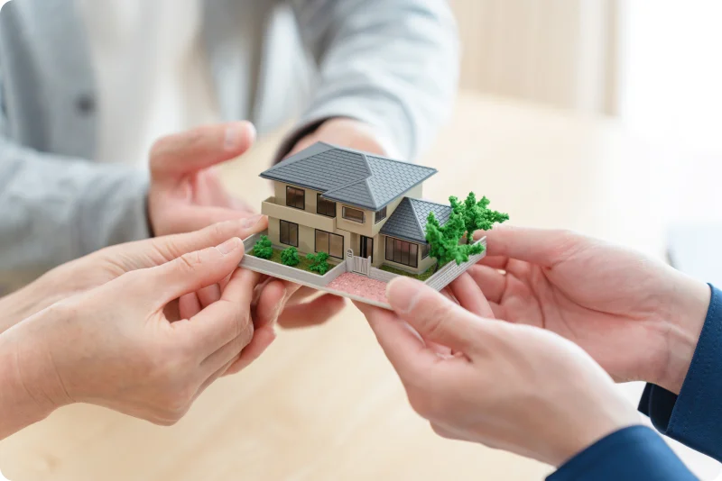 不動産取引をイメージした住宅模型のやりとり