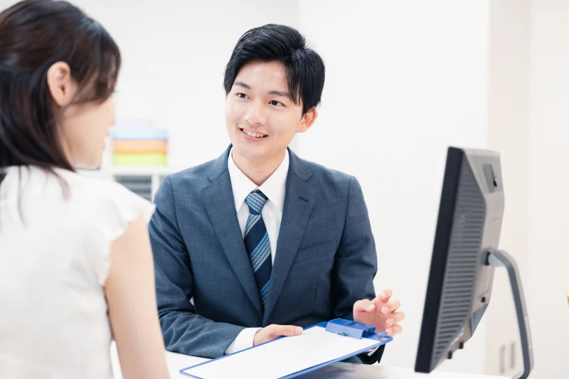 笑顔で相談対応するスーツ姿の男性スタッフ